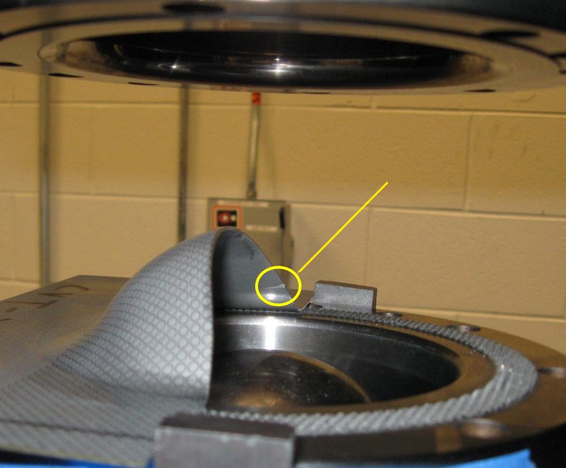 Figure 4: Half-Specimen Dome Test sample. Arrow points to edge crack.S-12